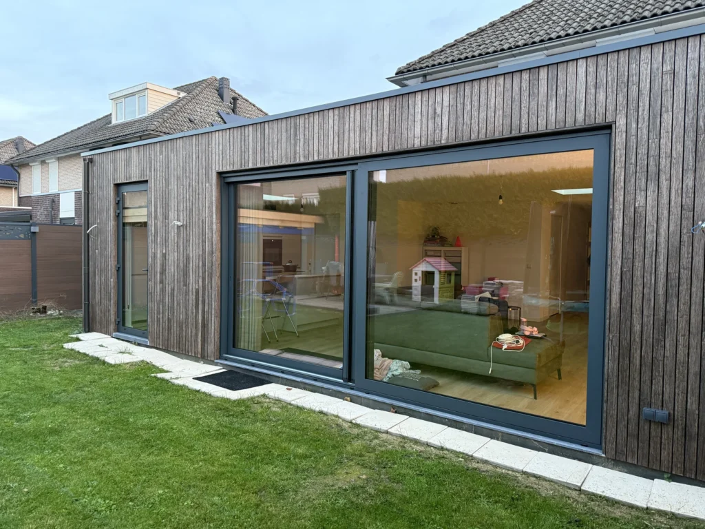 Houtskelet aanbouw met bamboe gevelbekleding en grote schuifpui in Born