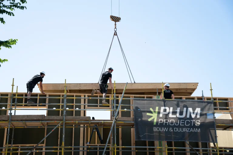 Prefab vloerelement wordt geplaatst bij nieuwbouw van Plum Projects, met het Plum Projects bouwdoek op de steiger
