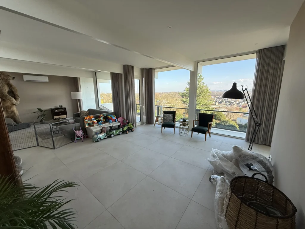 Gerenoveerde woonkamer met 90x90 tegelvloer en panoramaramen in Simpelveld